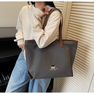 Detail of grey canvas tote bag with Docile girl embroidery and brown PU shoulder strap
