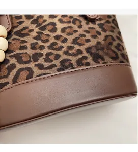 Close-up of leopard print fabric and brown leather join with gold embossed logo