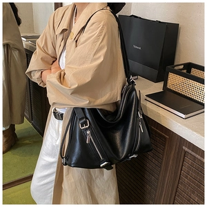 Detail of a black pebbled leather tote bag with functional zippers for urban casual style
