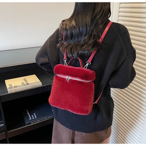 Red faux fur mini backpack on a black sweater with a plush texture and zip closure