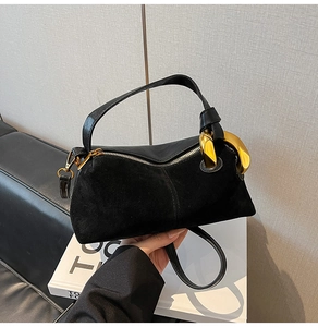 Detailed close-up of the large gold-tone metal knot on a black suede crossbody bag