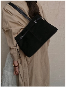 Sac cabas minimaliste en daim noir porté par un mannequin en robe kaki