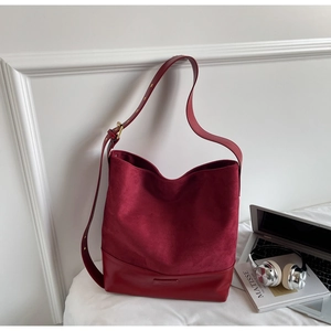 Detail of burgundy patchwork suede shoulder bag with adjustable strap and metal buckle