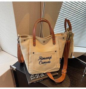 Detail shot of beige canvas bucket bag with brown leather straps reflected in a mirror