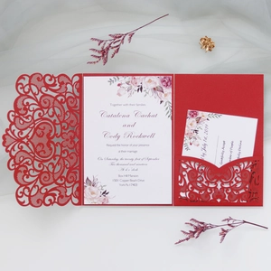 Detail of laser-cut burgundy wedding invitation with intricate hollow floral patterns