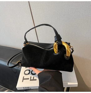 Close-up of black suede and leather handbag with oversized gold chain ring hardware