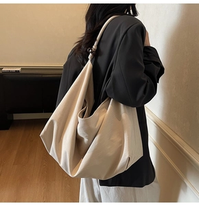 Minimalist beige canvas tote bag with spherical strap buckle shown in a lifestyle setting
