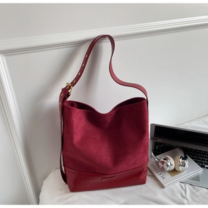 Detail of burgundy suede and smooth leather patchwork tote with adjustable strap