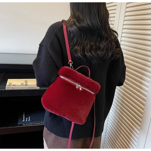 Detail of soft dark red faux fur backpack with leather straps on model in cozy interior