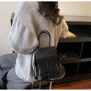 Détail d'un sac bandoulière en cuir noir chic avec de longues franges et deux poignées