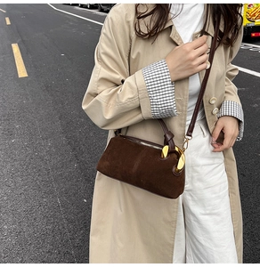 Detail of dark brown matte suede shoulder bag with decorative gold metal ring hardware