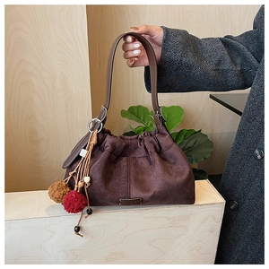 Vue détaillée du sac en daim marron avec plis et breloques à pompons colorés