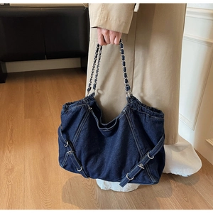 Detail of blue denim tote bag with contrast white stitching and silver chain strap