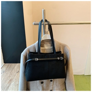 Vue détaillée du grand sac cabas noir en cuir givré avec boucle argentée sur manteau