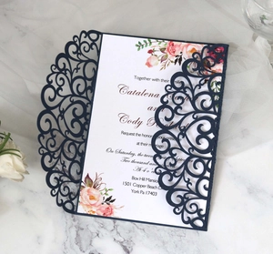 Detail showing the intricate laser-cut navy blue wedding invitation with floral insert