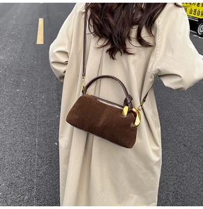 Detail of dark brown suede handbag featuring a signature large gold metal side buckle