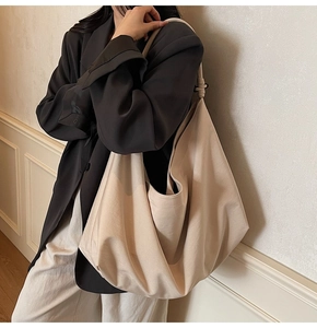 Detailed view of the large cream faux suede hobo bag draped on a shoulder strap