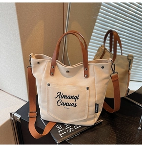 Detail of off-white canvas tote with brown leather handles and adjustable fabric strap