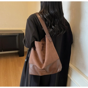 Detail view of brown suede and leather patchwork shoulder bag styled with black coat