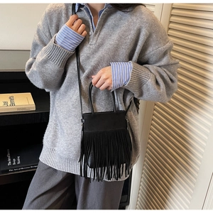 Détail du sac seau noir à franges avec de longs glands et une bandoulière amovible