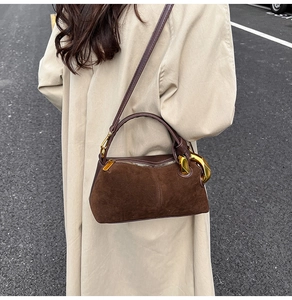Detail of vintage brown suede crossbody bag with gold hardware worn with a beige trench coat
