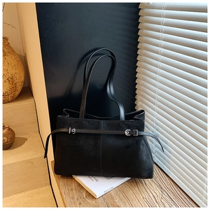 Détail d'un grand sac cabas vintage en cuir noir mat avec boucles argentées sur un banc