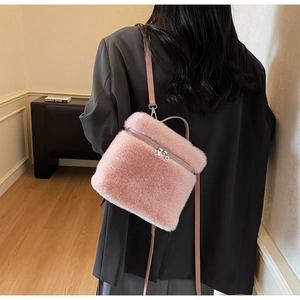 Detailed macro view of pink faux fur texture and silver zipper on women's crossbody bag