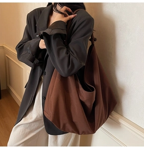 Detail of a large brown suede hobo bag featuring knotted shoulder strap on a model