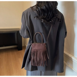 Sac seau vintage marron à franges porté par un mannequin avec texture en cuir mat