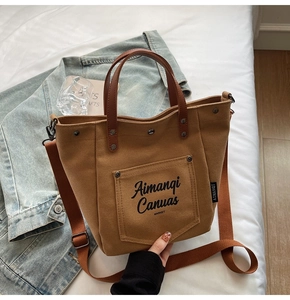 Detailed view of brown canvas tote bag with faux leather straps and front pocket print