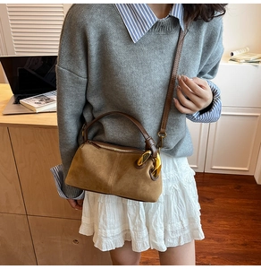 Close-up of vintage brown suede shoulder bag with gold chain on model's outfit