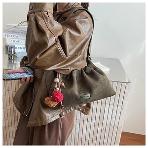 Détail du sac seau en daim vert olive avec plis élégants et logo de marque en métal