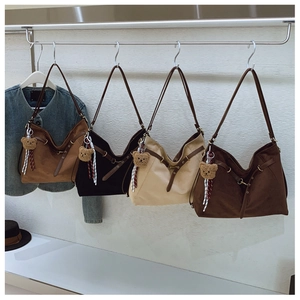 Detailed display of four suede hobo bags with cute bear charms and adjustable straps