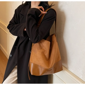 Macro detail of brown suede and smooth leather stitching with metal rivets on tote bag
