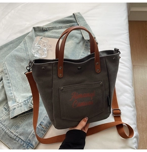 Detail of grey canvas tote bag with brown leather handles and adjustable shoulder strap