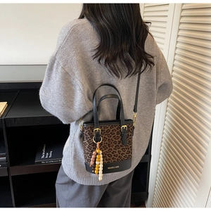 Leopard print bucket bag detail featuring wooden bead charm and black leather handle
