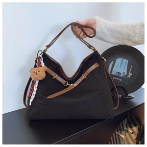 Dettaglio borsa hobo in camoscio nero con tracolla marrone e ciondolo a forma di orso