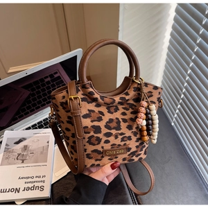 Macro detail of the leopard print handbag showing the tassel and adjustable strap