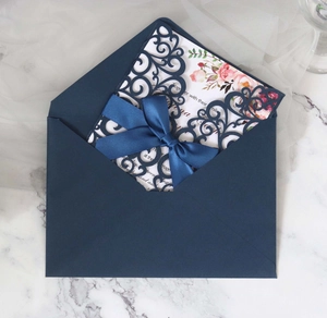 Detailed laser-cut navy wedding invitation with satin bow and floral inner page