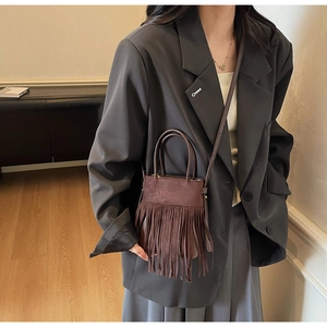 Détail d'un sac à bandoulière en daim marron foncé avec de longues franges sur le mannequin