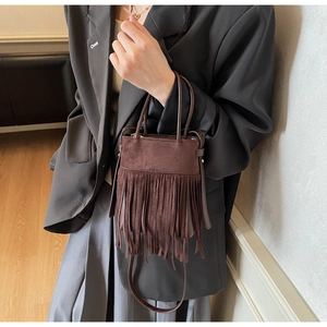 Détail du sac seau en daim marron foncé avec de longues franges de style vintage