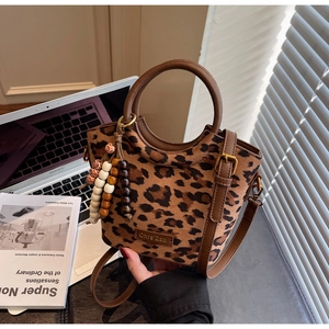 Detail of leopard print bucket bag with brown leather ring handle and beaded charm accessory