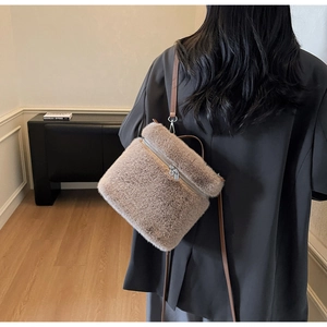 Detail of plush faux fur texture and leather strap on a chic autumn crossbody bag