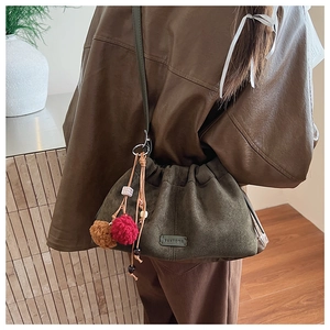 Détail du sac nuage en daim vert foncé avec pompons en peluche et patch cuir PANTODR