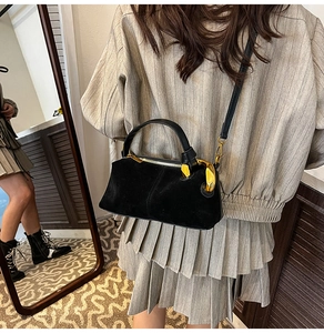 Detail of vintage black suede handbag with gold metal hardware and leather straps