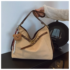 Dettaglio della borsa tote in pelle scamosciata beige con tracolle in cuoio marrone