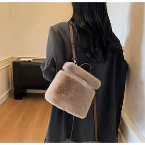 Rear view of a model wearing the brown faux fur backpack with slim leather straps