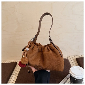 Détail du sac seau en daim marron avec cordon de serrage et pompon décoratif en fourrure