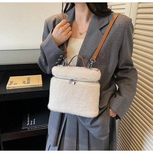 Detail of white plush handbag featuring brown leather handles and adjustable shoulder strap