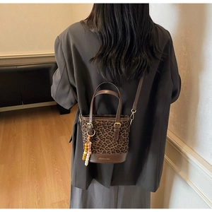 Detailed look at leopard print bucket bag featuring brown leather trim and golden hardware